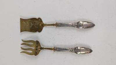 une paire d'ustensiles de table anciens en argent posés sur une surface blanche