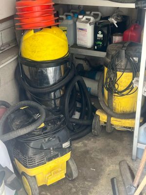 un aspirateur jaune et noir et d'autres équipements de nettoyage dans un garage