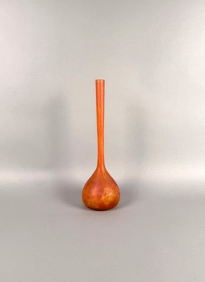 a small orange vase sitting on a white surface