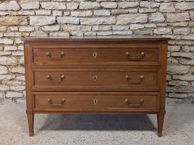 an antique chest of drawers against a stone wall