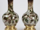 paire de vases ornés de motifs floraux sur fond blanc, avec des bases dorées
