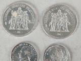 four different british coins sitting on top of a white surface