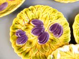 des assiettes jaunes et violettes ornées de fleurs violettes, posées sur une table