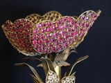 a gold vase with a pink flower on top of it
