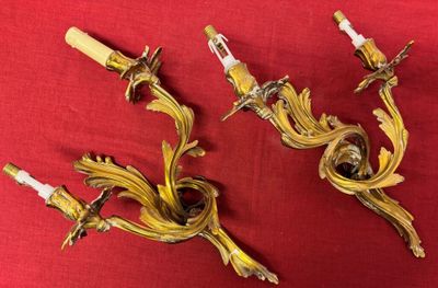 pair of antique brass wall sconces on a red cloth