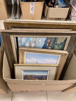 une boîte remplie d'œuvres d'art encadrées, exposées dans un magasin