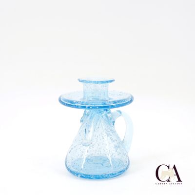 un vase en verre bleu muni d'une anse, sur fond blanc