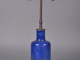 une image représentant un vase bleu sur lequel est posée une lampe