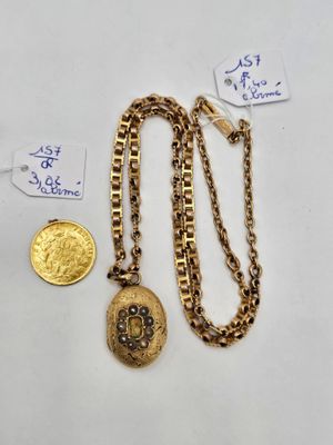 a close up of a gold necklace with a coin on a table