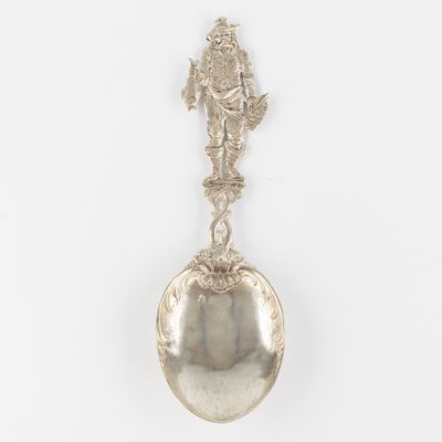 un gros plan d'une cuillère en argent ornée d'une statuette