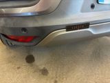 the rear end of a silver car with a sticker on it ' s bumper