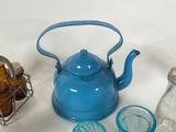 a blue tea kettle sitting on top of a table next to other glassware