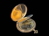 a gold pocket watch sitting on a black surface
