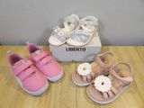 two pairs of baby shoes are sitting on a table next to a shoe box