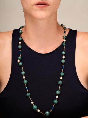 La femme porte un débardeur noir et un collier vert orné de perles.