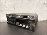 a close up of a stereo player on a table with a brick wall in the background