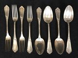 six spoons and six forks are lined up on a black surface