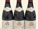 trois bouteilles de vin rouge posées l'une à côté de l'autre sur une surface blanche