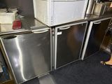 a woman standing in a kitchen next to two refrigerators