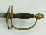 a sword with a gold handle on a white surface