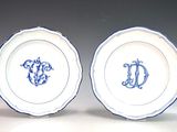 une paire d'assiettes bleues et blanches ornées de lettres formant un monogramme
