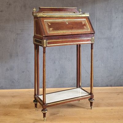 an antique writing desk with a marble top on a wooden floor