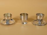 trois tasses et soucoupes en argent sont posées sur une table