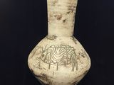 un vase blanc orné d'un motif sur fond noir