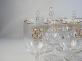 several wine glasses with gold designs are lined up on a white surface