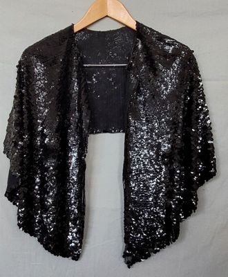 a black sequinned jacket hanging on a hanger on a wall