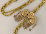 chaîne en or jaune ornée de perles et de pompons sur un fond blanc