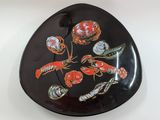 an image of a black plate with lobsters and shells on it