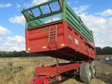 a red trailer with a green top parked in a field