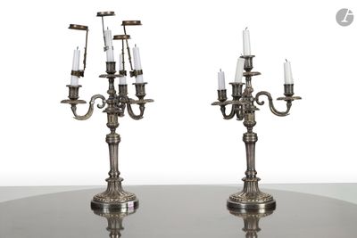 une paire de chandeliers plaqués argent avec des bougies posés sur une table en verre