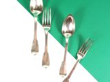 trois cuillères et deux fourchettes sur une table verte et blanche