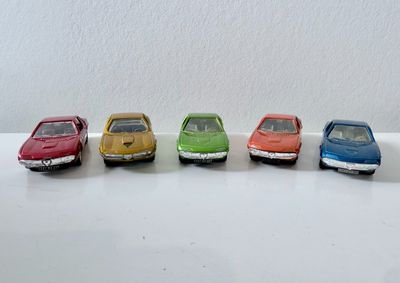 cinq petites voitures sont alignées en rang sur une surface blanche