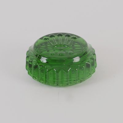 un récipient en verre vert muni d'un couvercle, posé sur une surface blanche