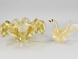 deux oiseaux en verre jaune posés l'un à côté de l'autre sur une surface blanche