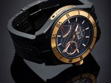the black and gold watch is sitting on a black surface