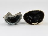 two pieces of black and white marble sitting next to each other on a white surface