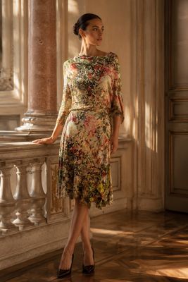 une femme debout sur un balcon, vêtue d'une robe