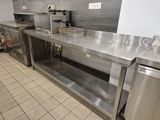 plans de travail en acier inoxydable dans une cuisine professionnelle équipée d'appareils électroménagers en acier inoxydable