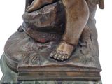 a bronze statue of a child sitting on top of a rock