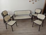 plusieurs chaises et une table dans une pièce où est accrochée une horloge au mur