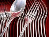 a lot of silver spoons and forks on a red tray