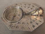 a silver clock with roman numerals on it on a table