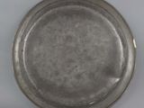 an old silver plate on a white table with a white background