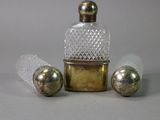 a small glass bottle with a gold lid and three silver balls