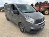 a grey van parked in a lot with a tractor behind it
