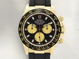 La montre est noire et dorée, avec un cadran jaune.